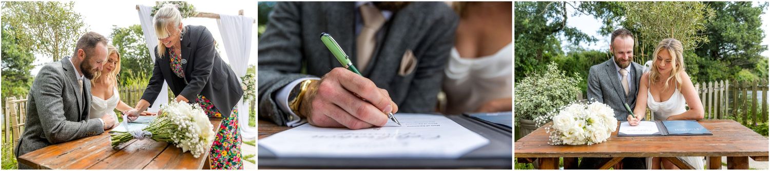 Wedding ceremony documents being signed at a rustic wooden table outdoors.