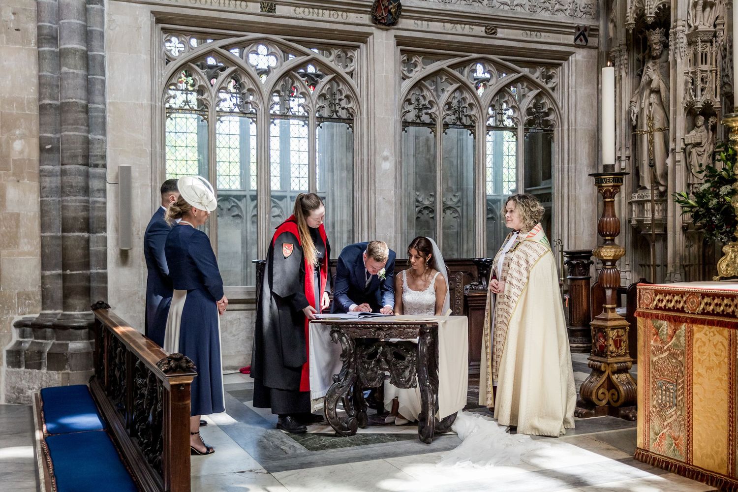 Wedding ceremony in progress under soaring gothic arches and stained glass windows.
