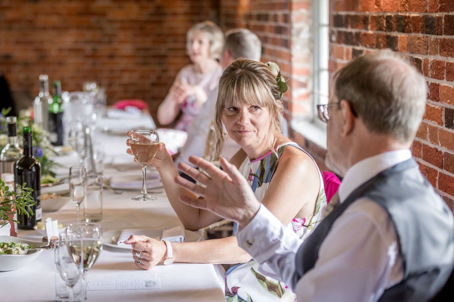Wedding reception tables set against exposed brick walls with natural light streaming through windows.
