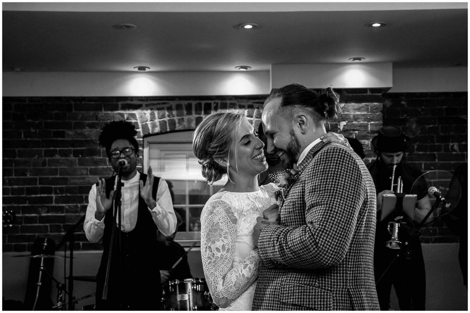 Dramatic black and white wedding reception photos with spotlight effects in brick venue.