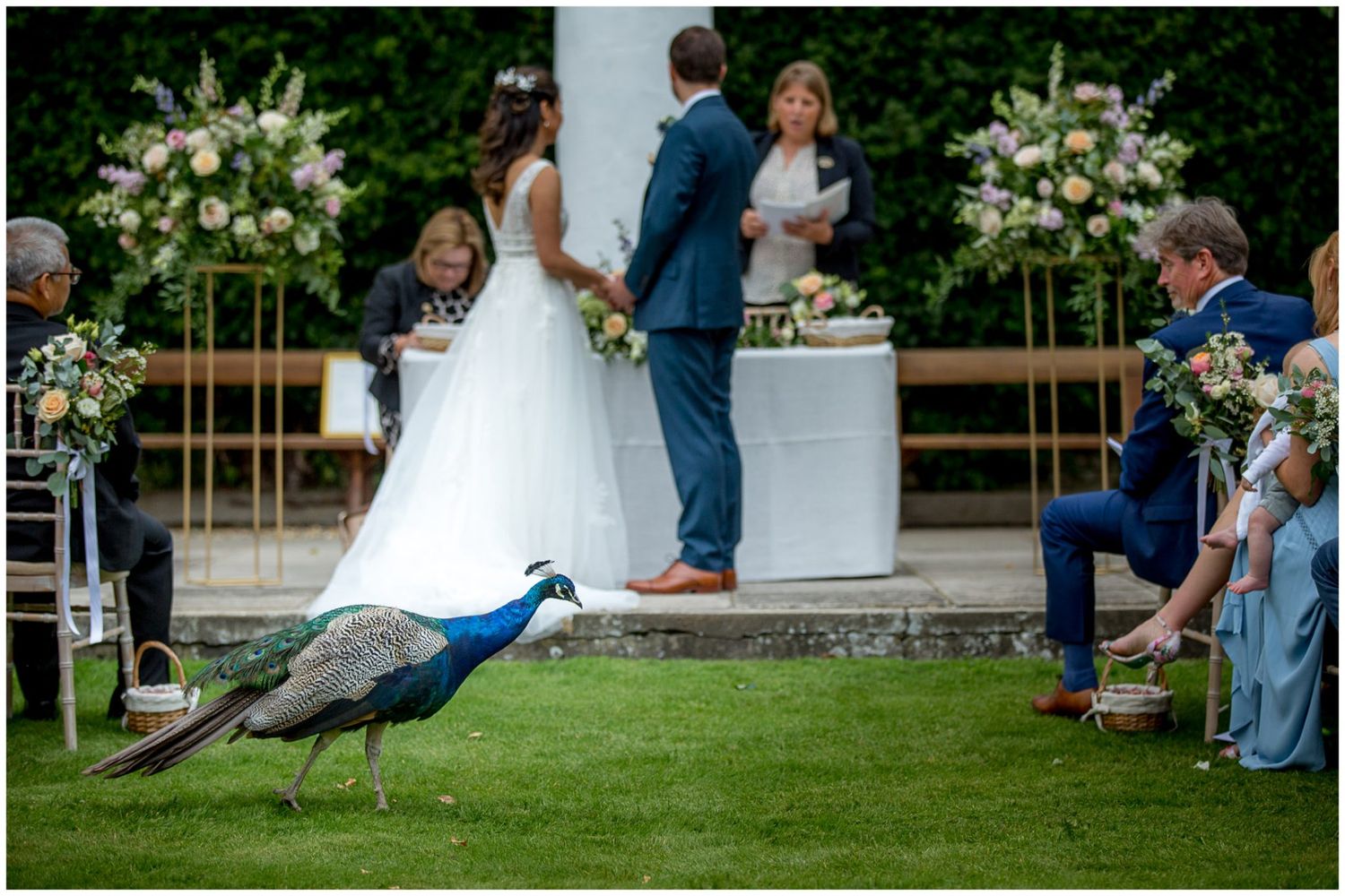 Wedding ceremony setup with floral arrangements and seating on a manicured lawn.