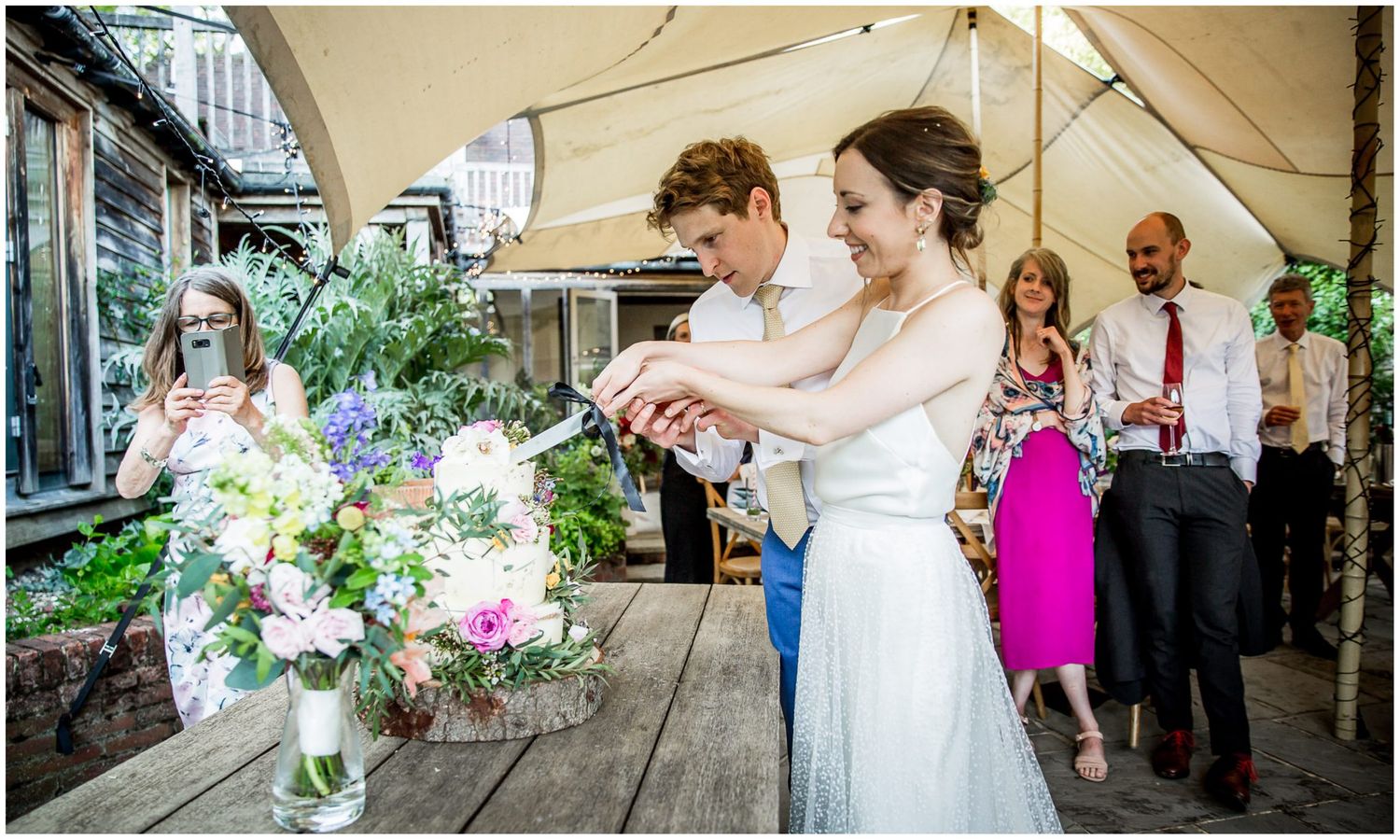 Wedding party celebrates under a covered porch with floral decorations.