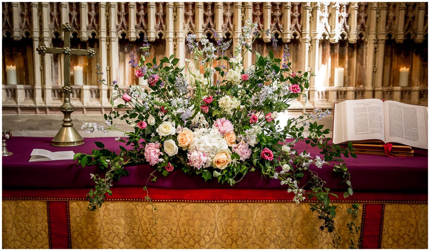 Elegant church altar decorated with cascading floral arrangements in white and pink with greenery accents.