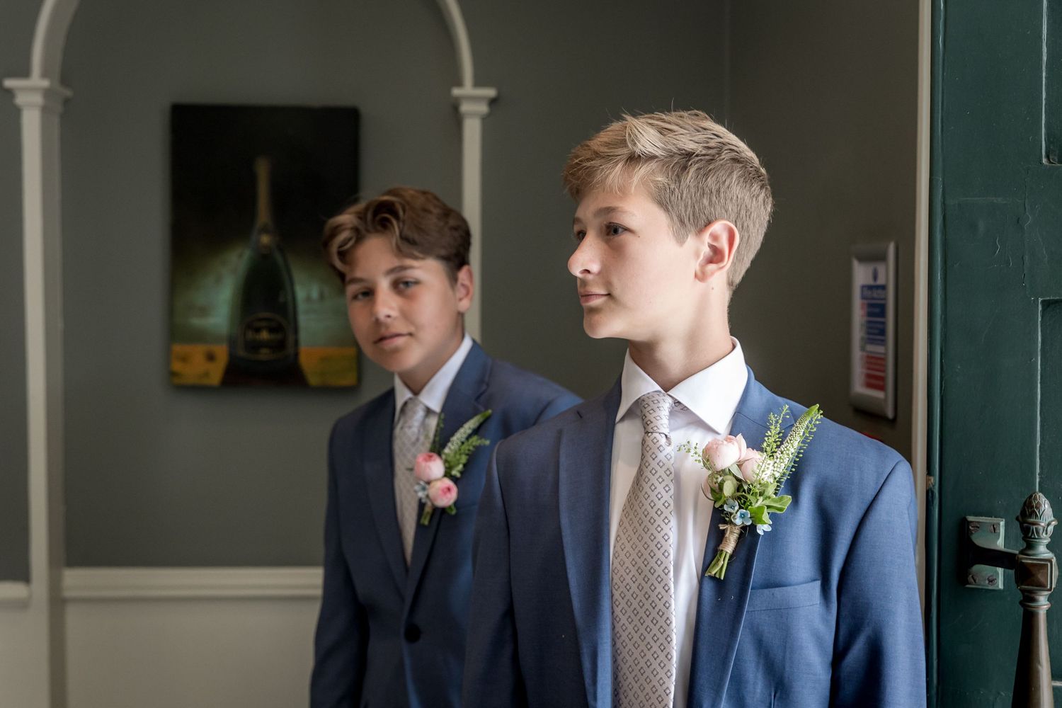 Young groomsmen in navy suits standing in front of white columns.