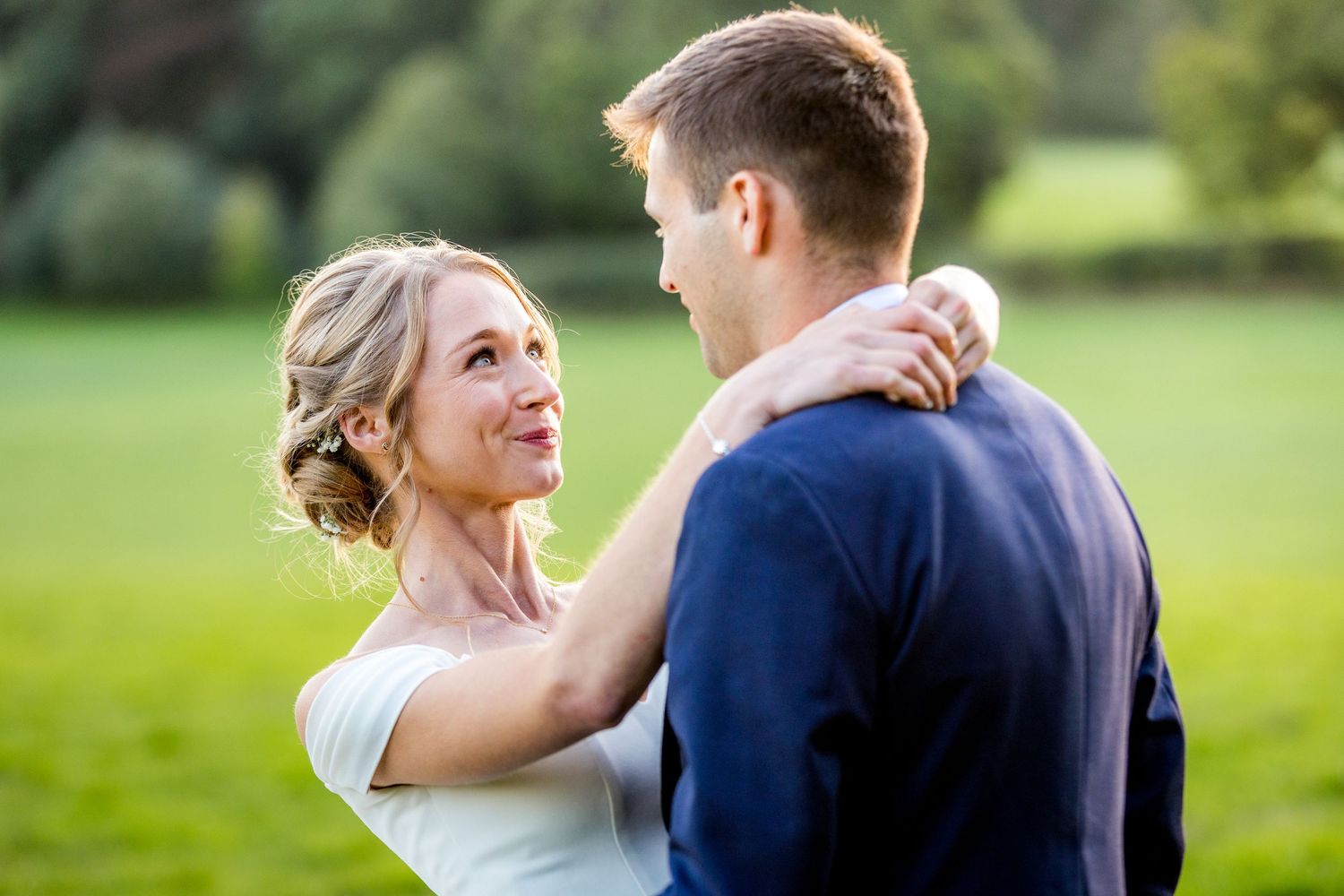 Newlyweds share an intimate dance outdoors during golden hour at their wedding celebration.