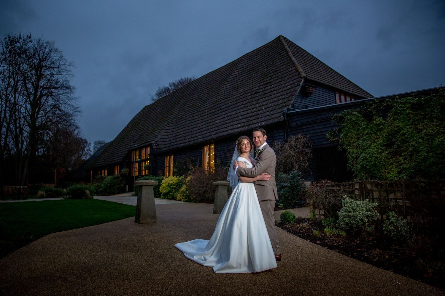 A wedding couple photographed in low light outside Clock Barn wedding venue