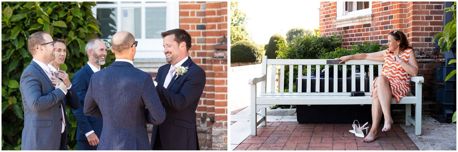 Groomsmen in suits chatting outdoors near brick wall while a woman sits on a white bench at Walhampton School