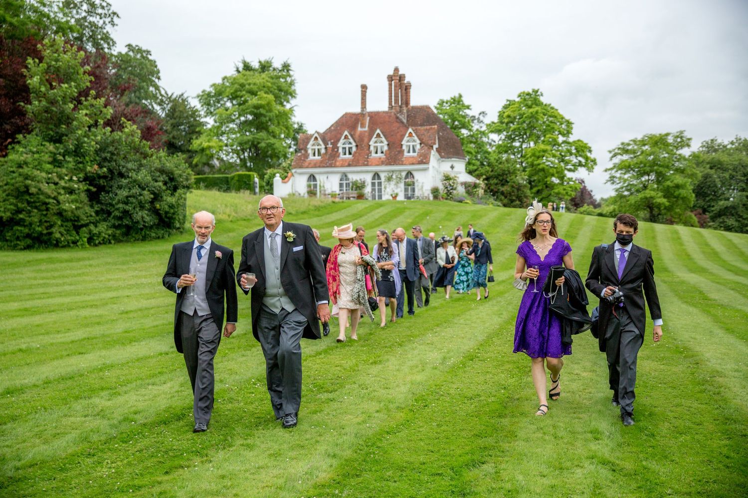 Wedding party walks from Houghton Lodge main house towards the reception marquee