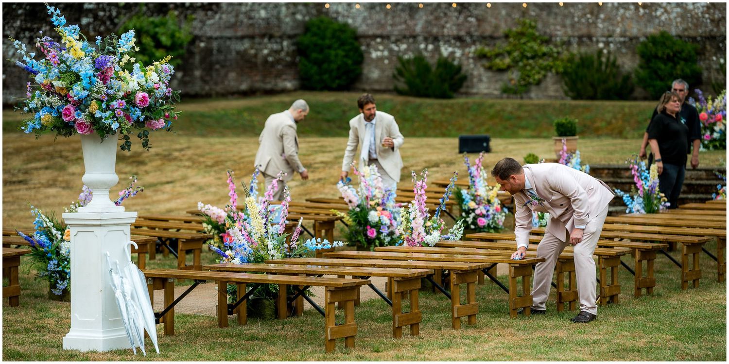Wedding guests help to dry the seating for the outdoor wedding as the rain stops.