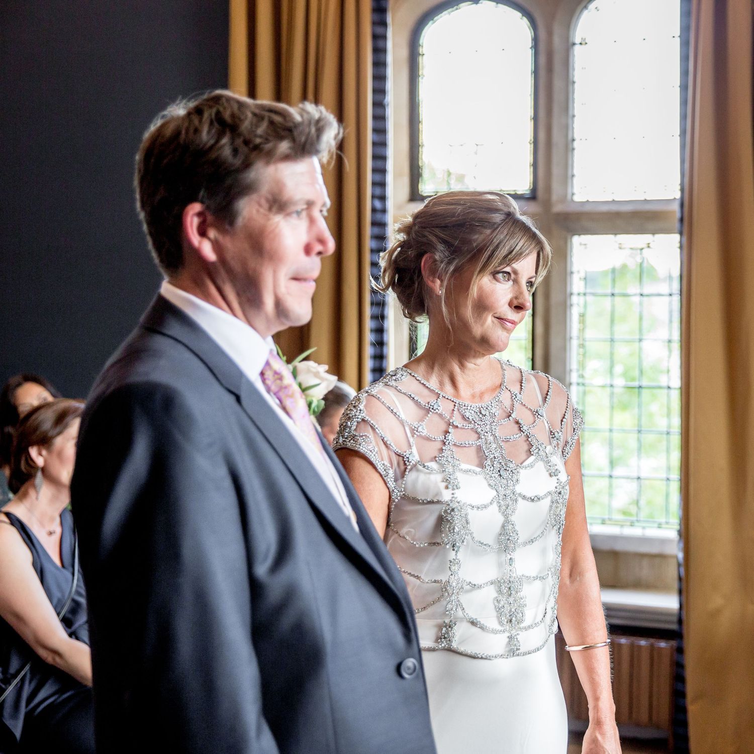 Wedding ceremony moment by large window in historic venue.