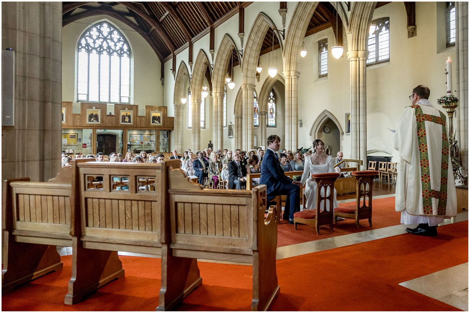 Interior view of a church with Gothic arches and stained glass windows during a ceremony.
