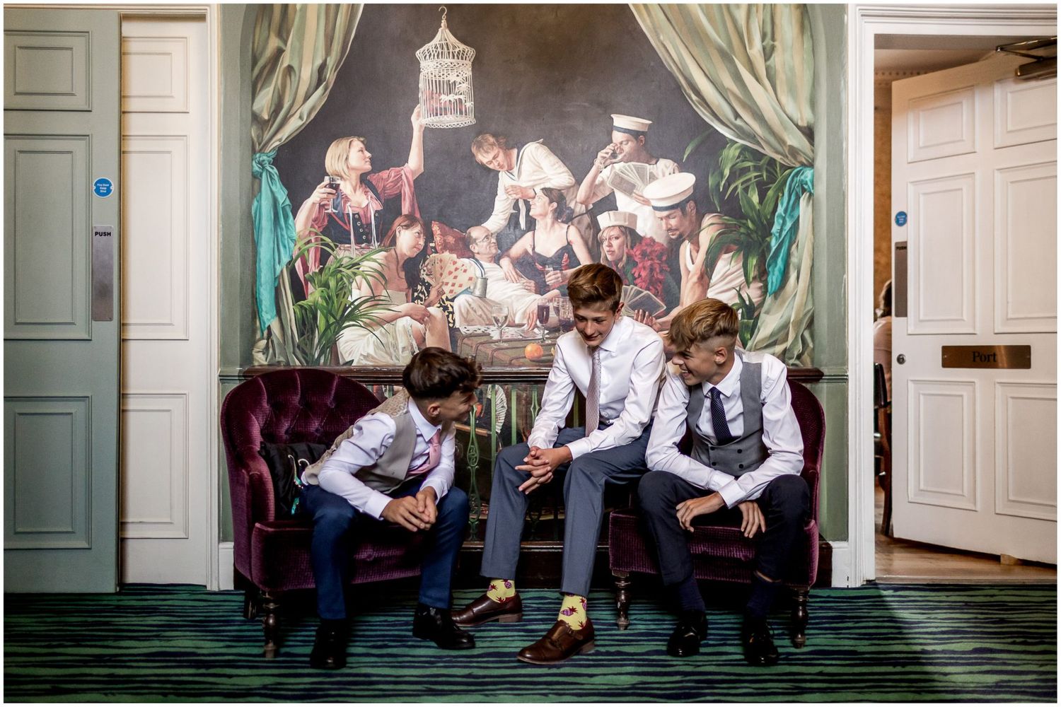 Wedding party posing in formal attire against elegant interior backdrop.