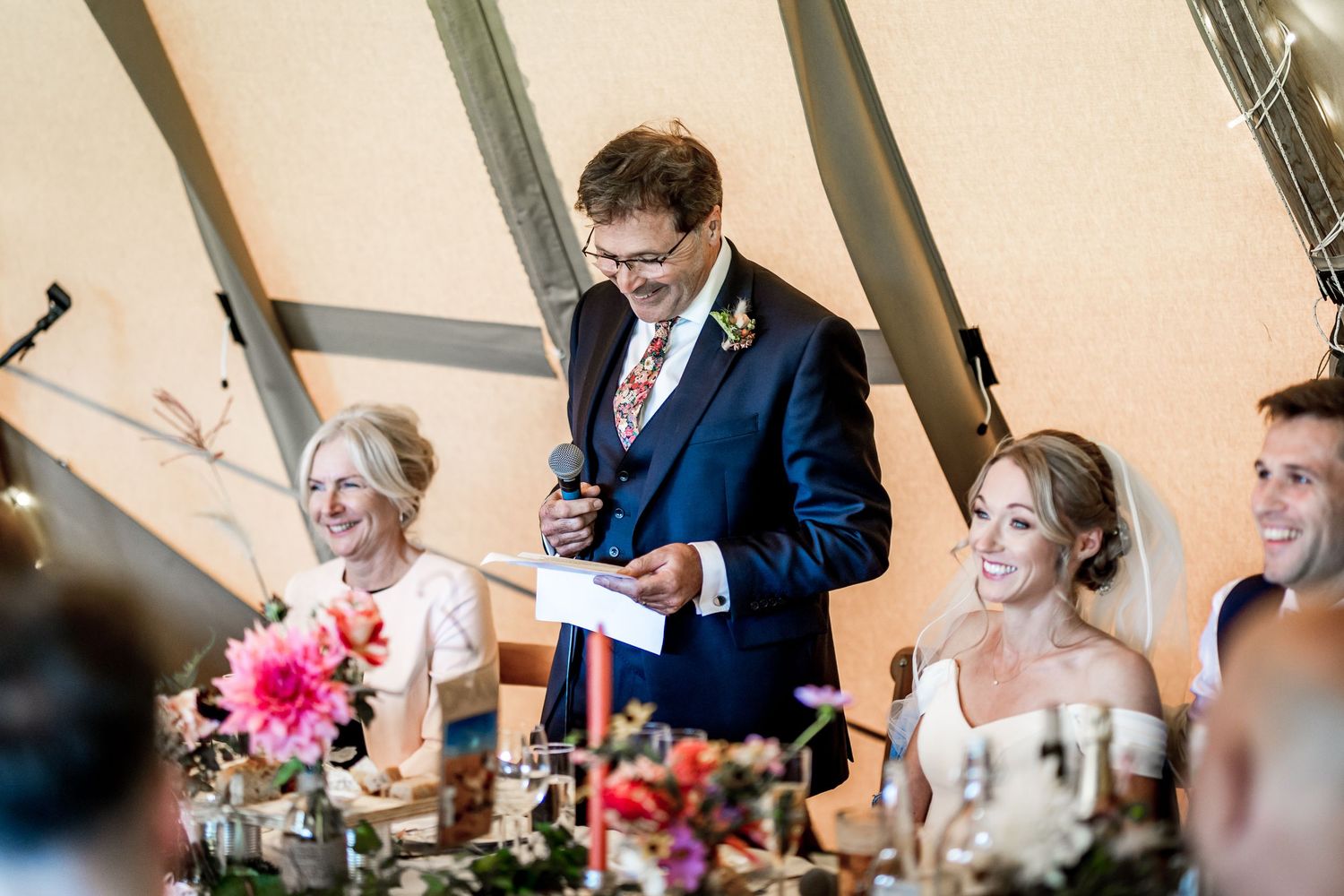 Wedding reception speeches and toasts being given inside a decorated tipi tent.