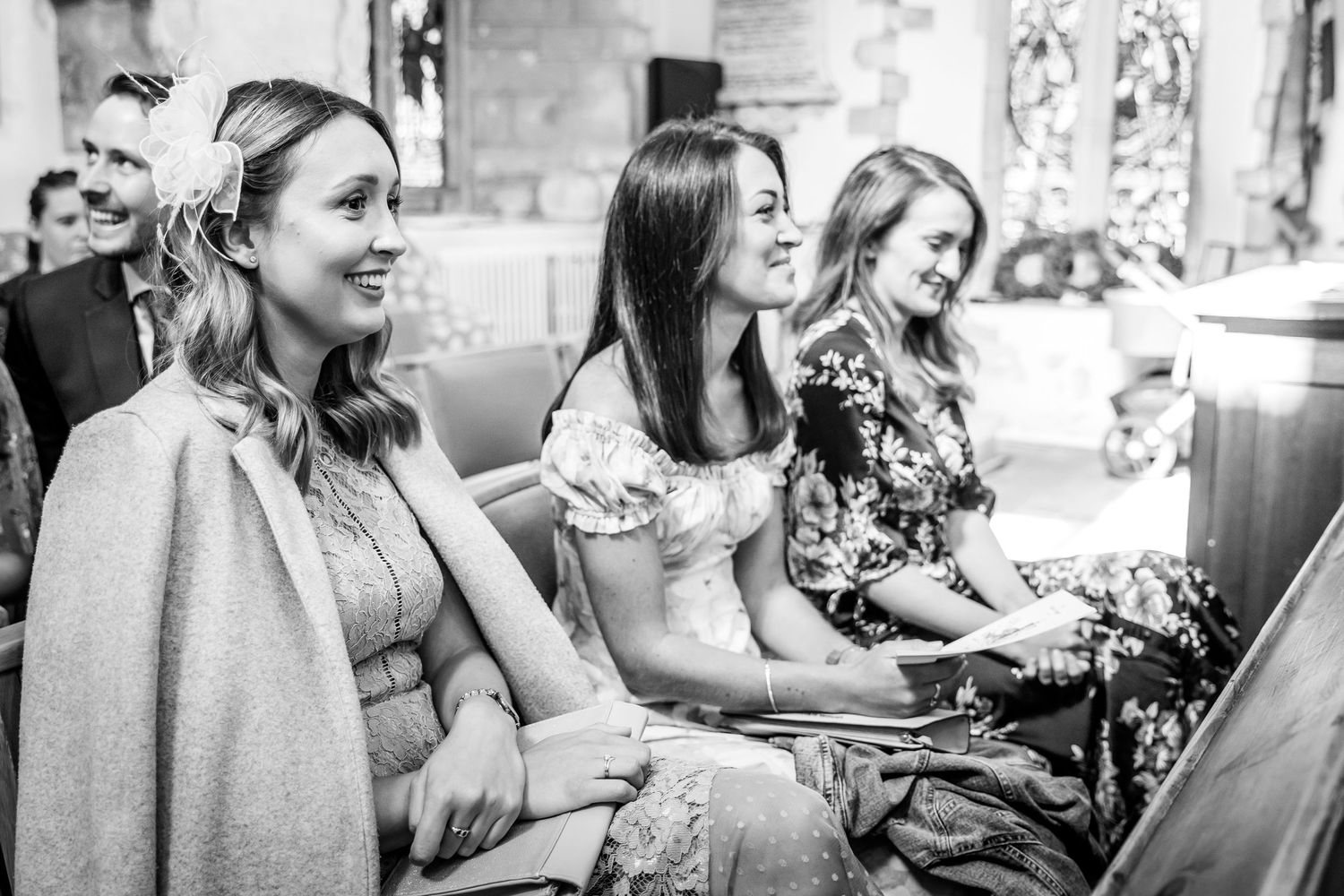 Wedding guests sharing joyful moments during the church ceremony.