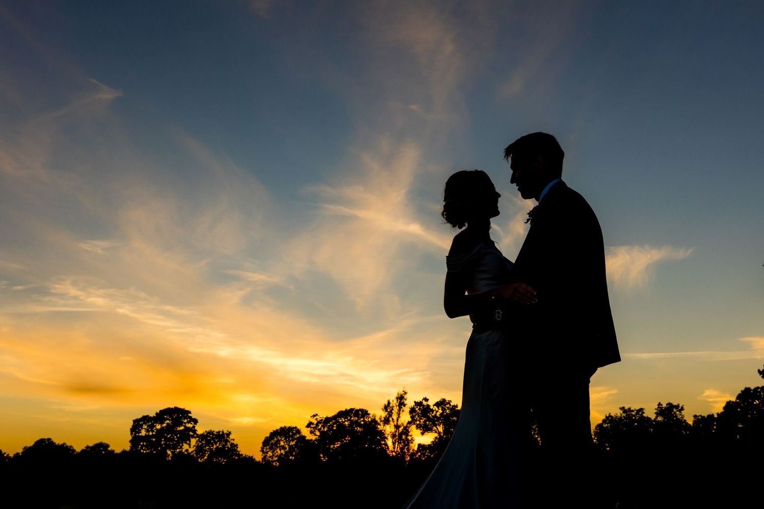 Dramatic silhouettes of a couple against a vibrant orange and blue sunset sky.