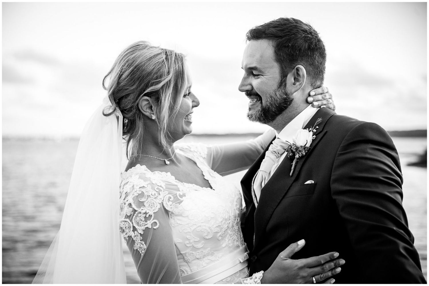 A romantic black and white wedding photo series showing tender moments between newlyweds by the ocean.