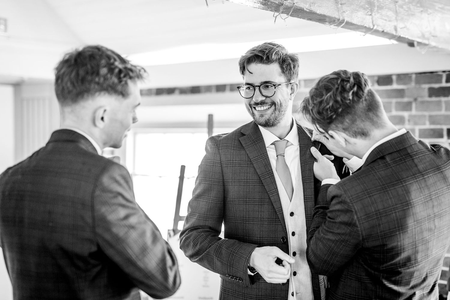 Two people in navy suits share an emotional moment during a wedding ceremony.