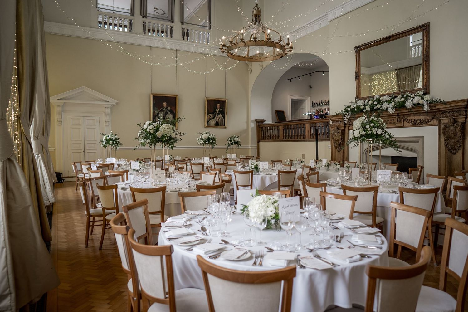 Elegant wedding reception hall with round tables set for formal dining under chandeliers.