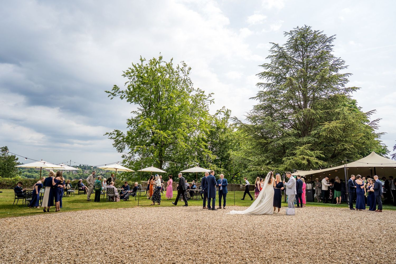 Panoramic view of wedding guests gathered on grounds of countryside venue.