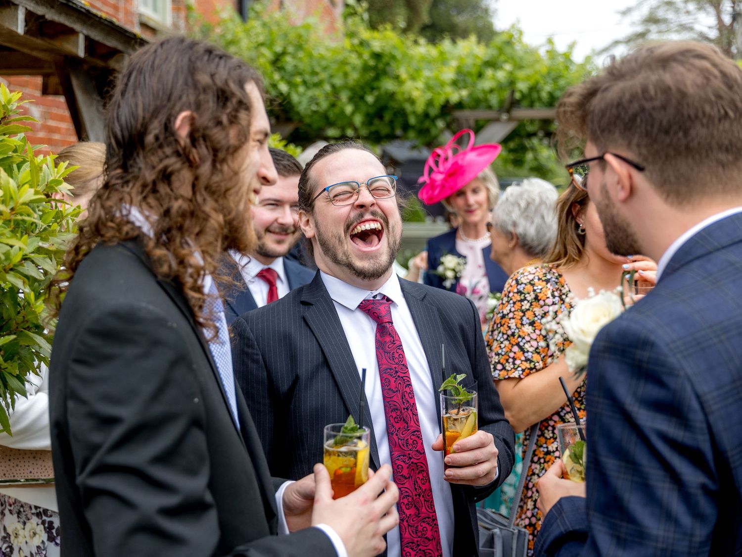 Wedding guests enjoying drinks and conversation at an outdoor reception.