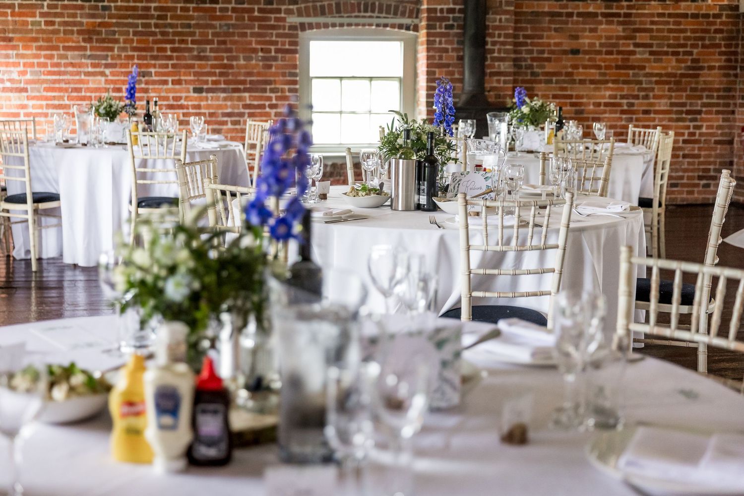 Elegant wedding reception tables set in rustic brick venue with blue accents.
