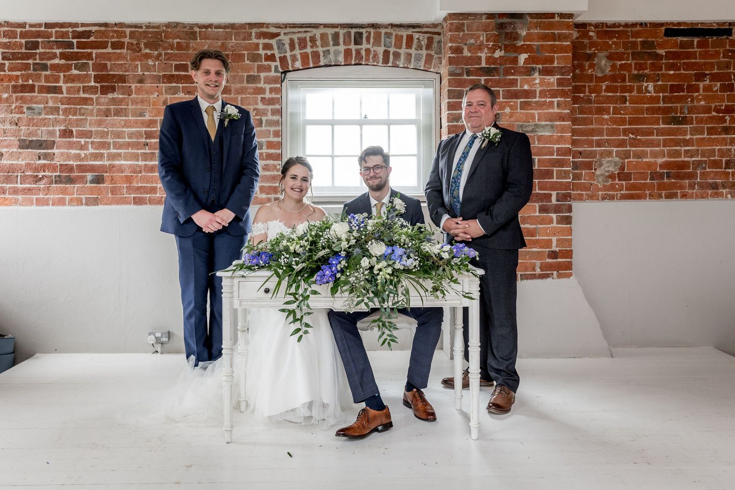 Wedding ceremony setup in industrial venue with white chairs and exposed brick walls.