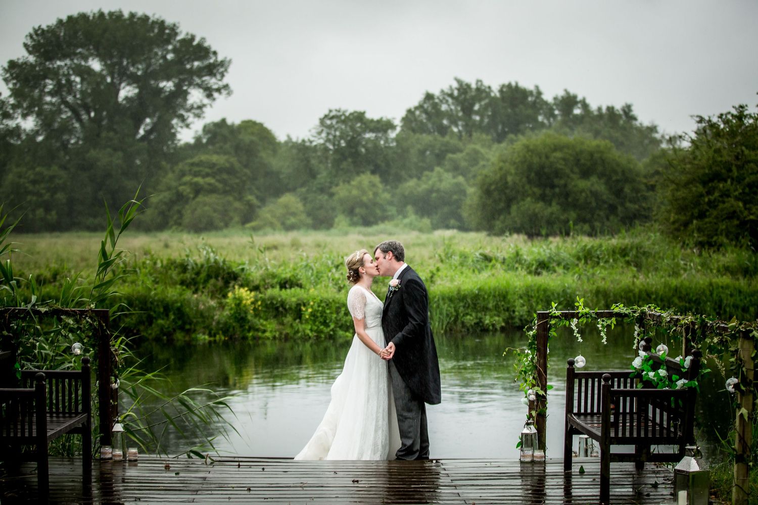 A bride and groom pose for their couple wedding photographs n the banks of the River Test at Houghton Lodge