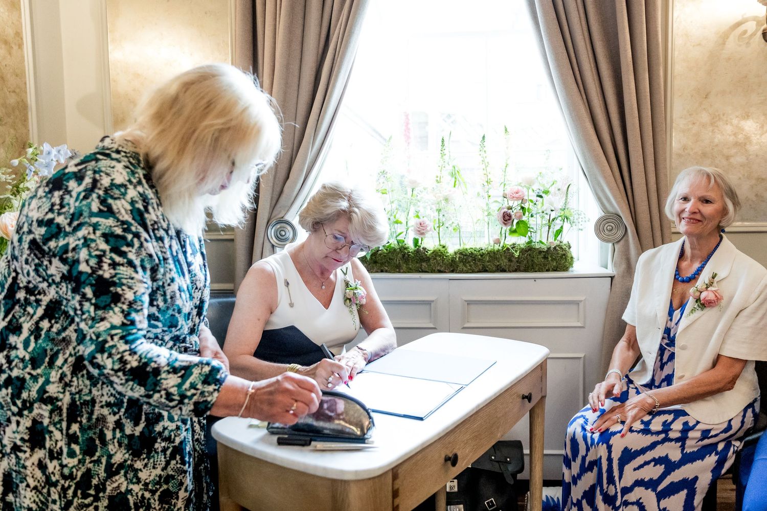Wedding guests gathered around a table during document signing ceremony.