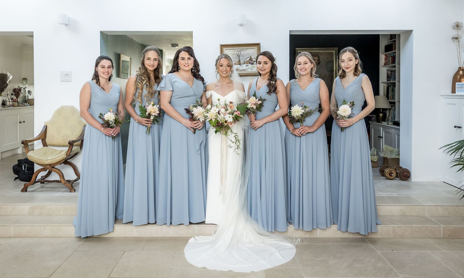 Bridesmaids in light blue dresses pose together during an elegant outdoor wedding celebration.
