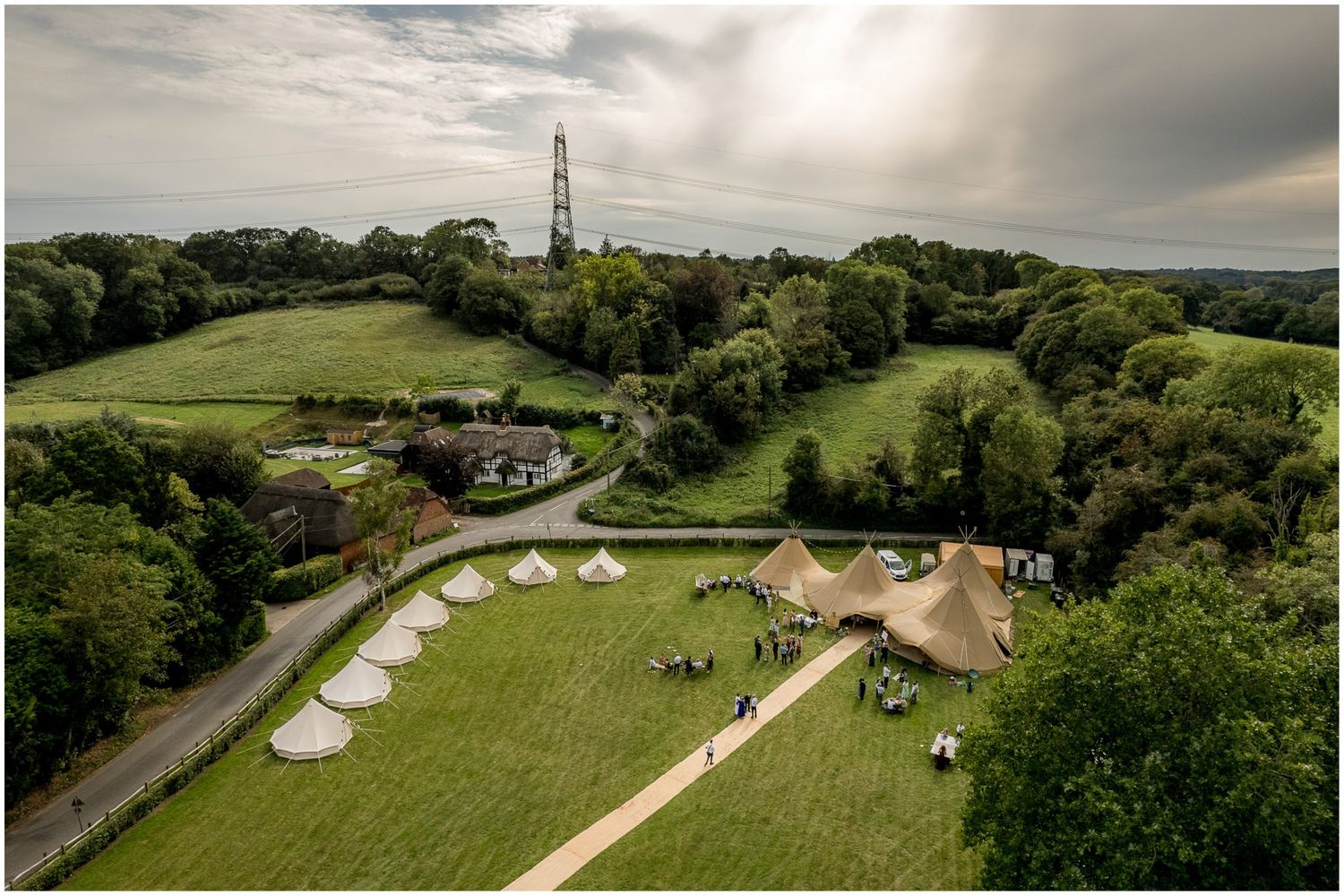 Aerial panoramic view of a countryside venue with multiple tipi tents.