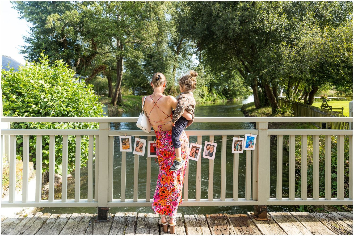 Decorated outdoor wedding venue with hanging photos and white fence details.