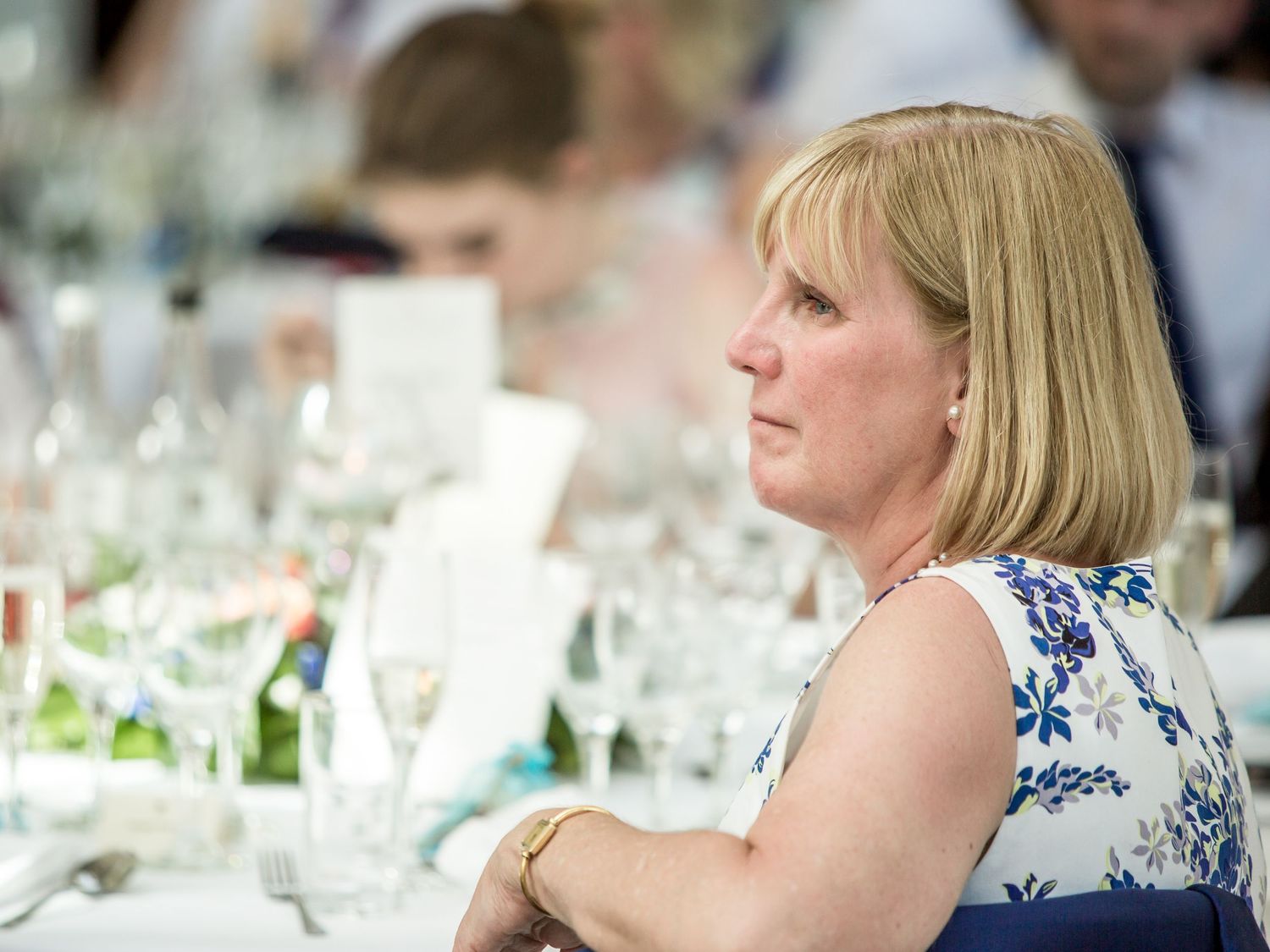 Wedding reception table settings with glassware and floral centerpieces.