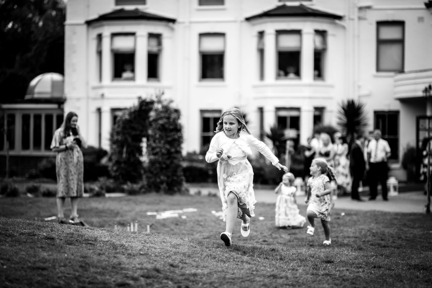 Black and white image of guests enjoying outdoor wedding festivities.