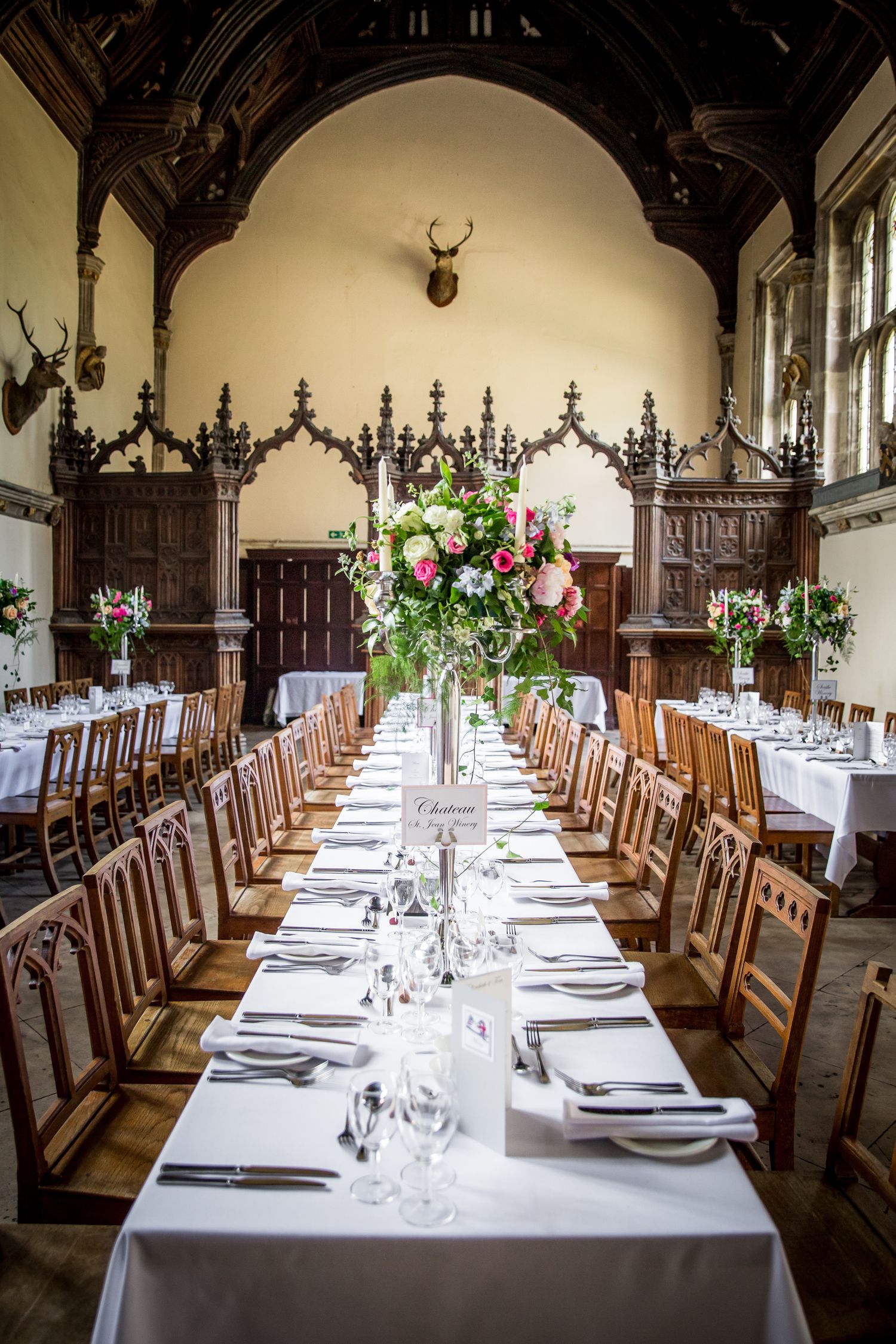 An elegant banquet hall set with long tables, white linens and floral centerpieces for a formal reception.