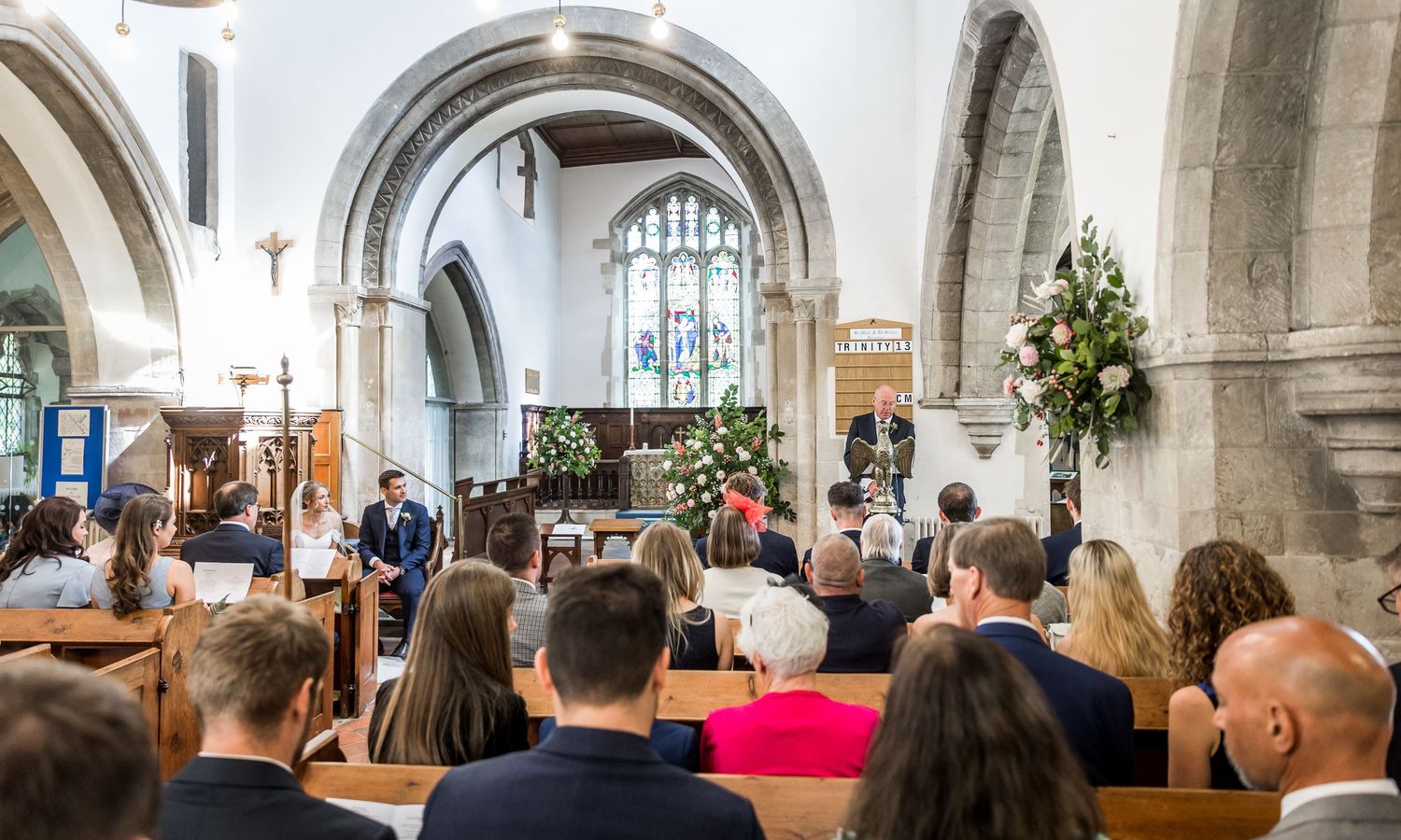 Wedding ceremony in a traditional church with stone arches and wooden pews.