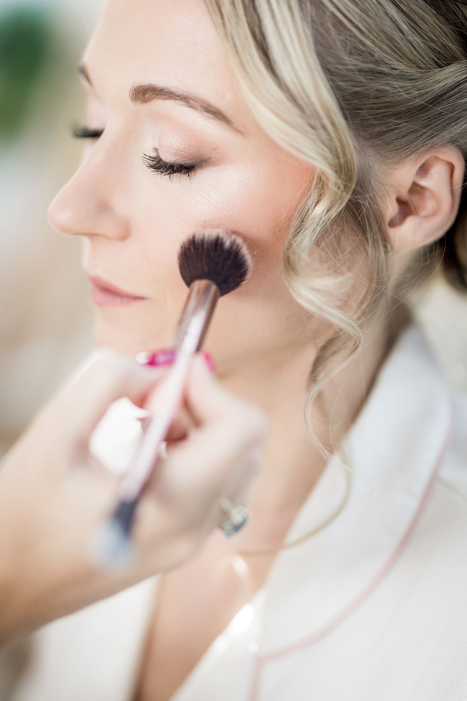 Close-up shots of makeup application using brushes and cosmetics during wedding preparations.