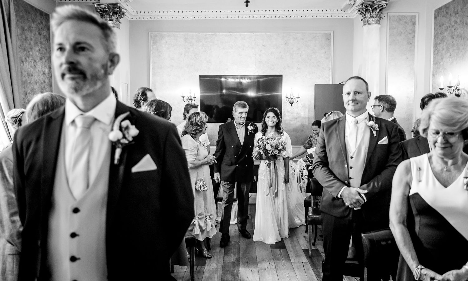 Black and white panoramic shot of wedding guests during reception festivities.