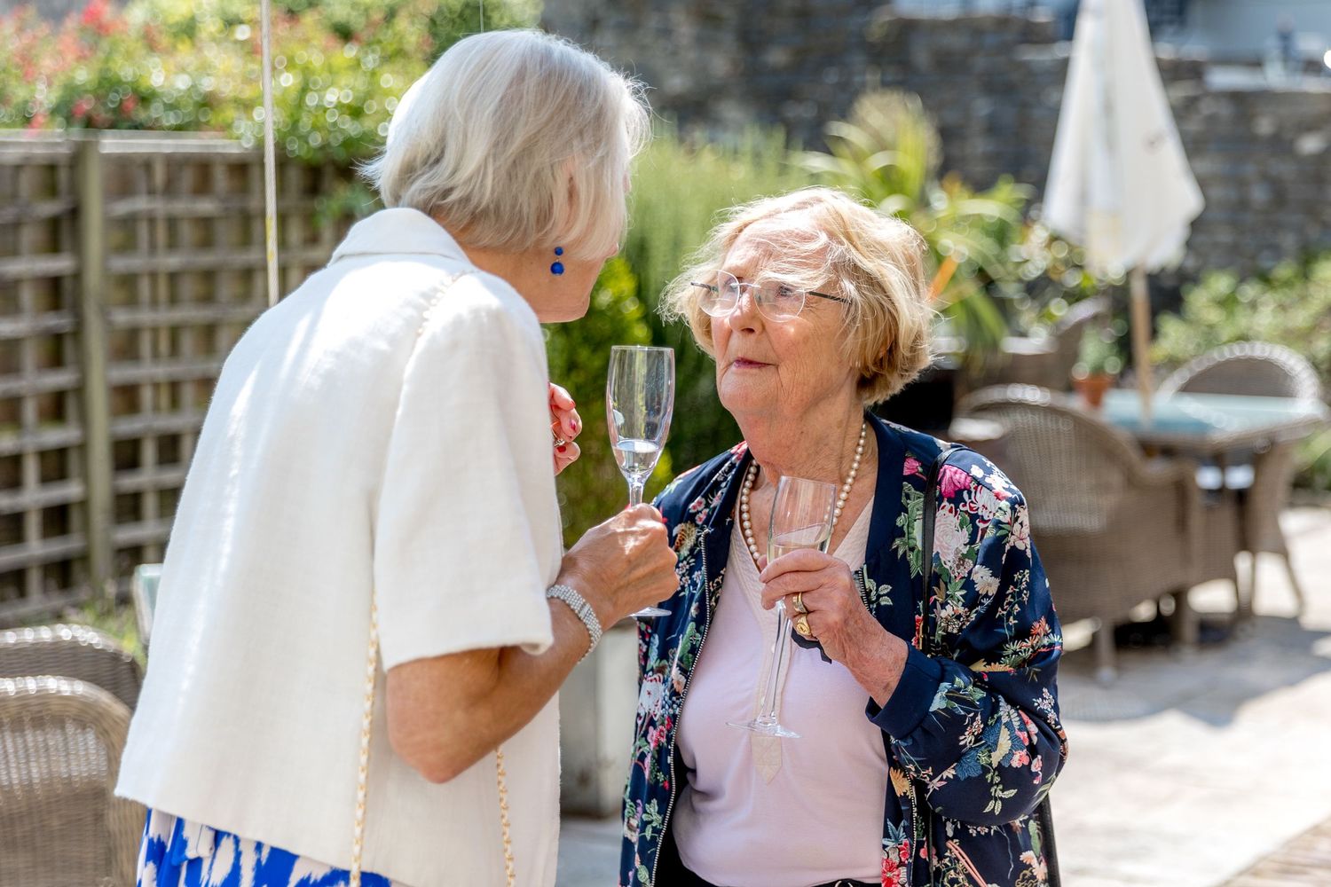 Garden party guests enjoying drinks and conversation in an outdoor setting.