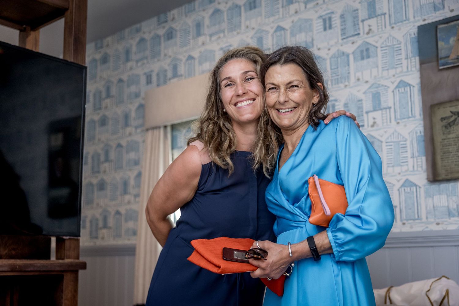 Joyful moments captured during wedding preparations against blue wallpapered background.