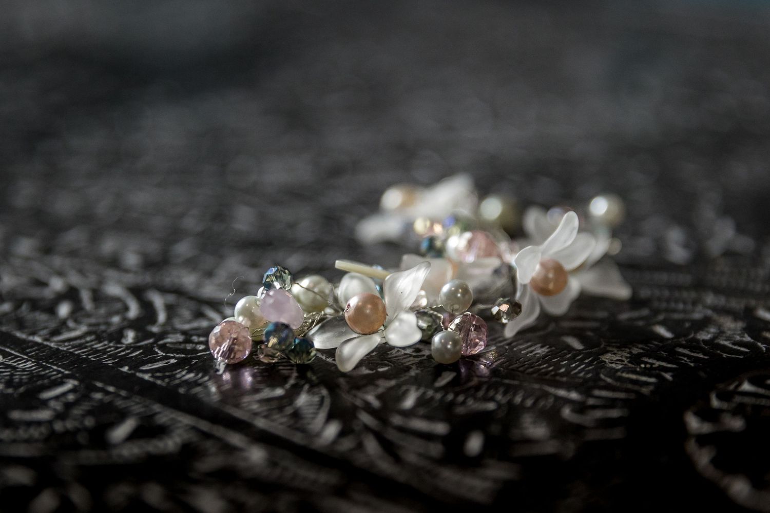 Delicate cherry blossoms arranged on dark textured lace fabric.