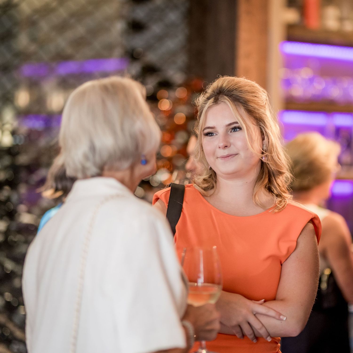 Guests in formal attire enjoying drinks and conversation at an evening event.