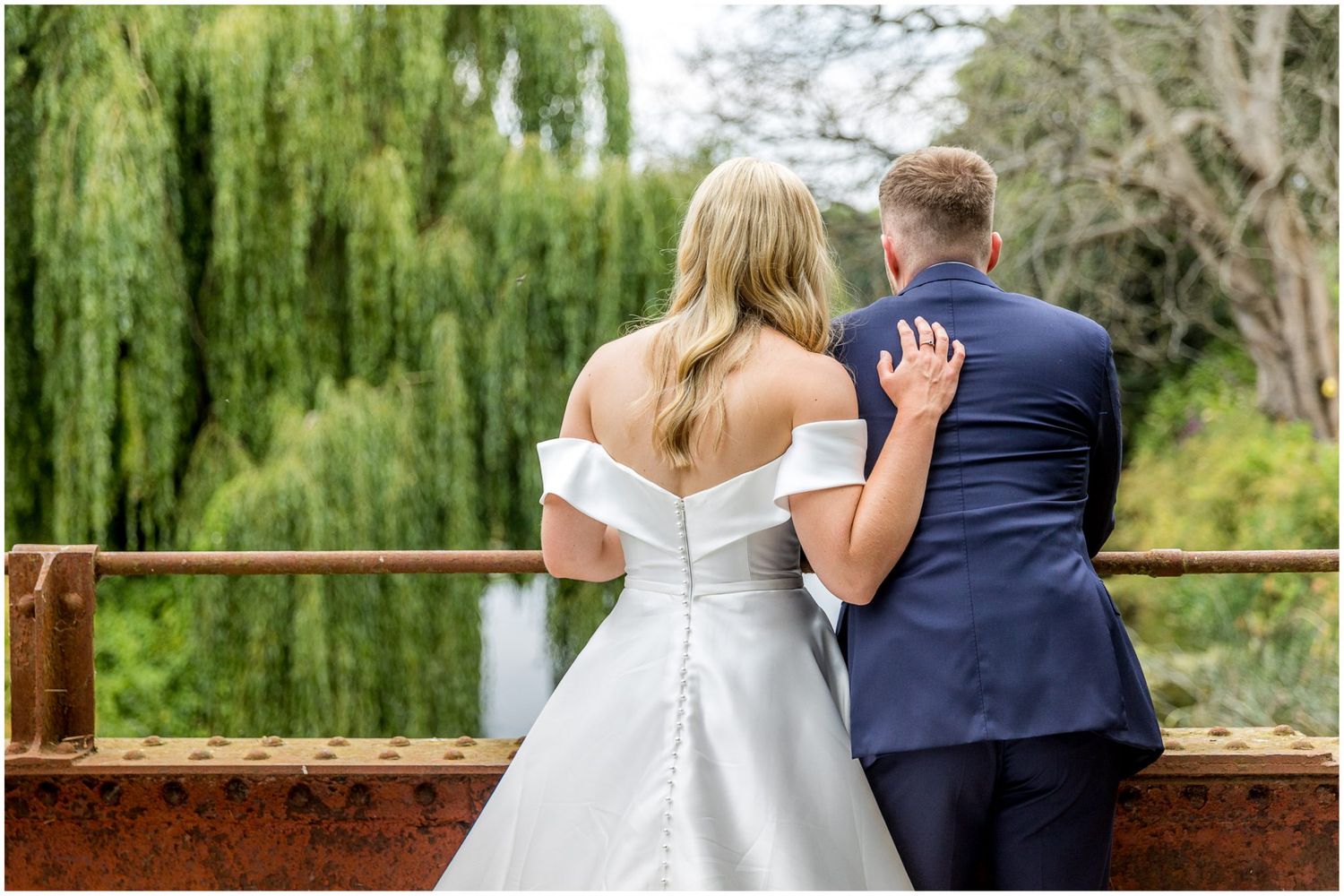 Couple sharing intimate moments by a willow tree near water.