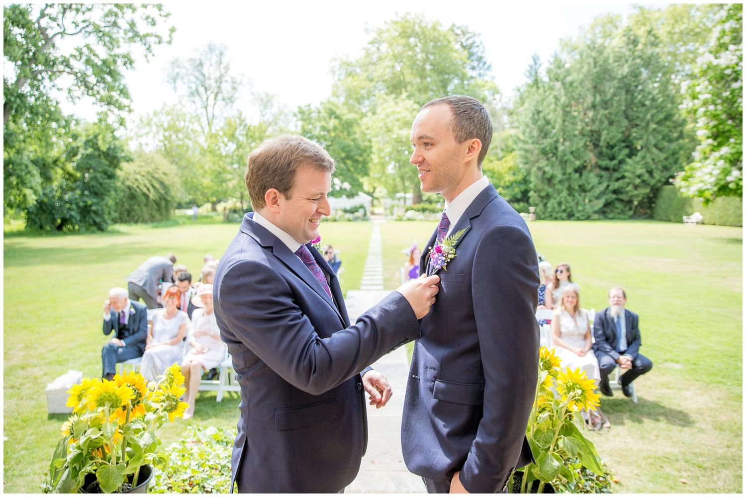 Two people in formal attire share an intimate moment while standing in a garden setting.