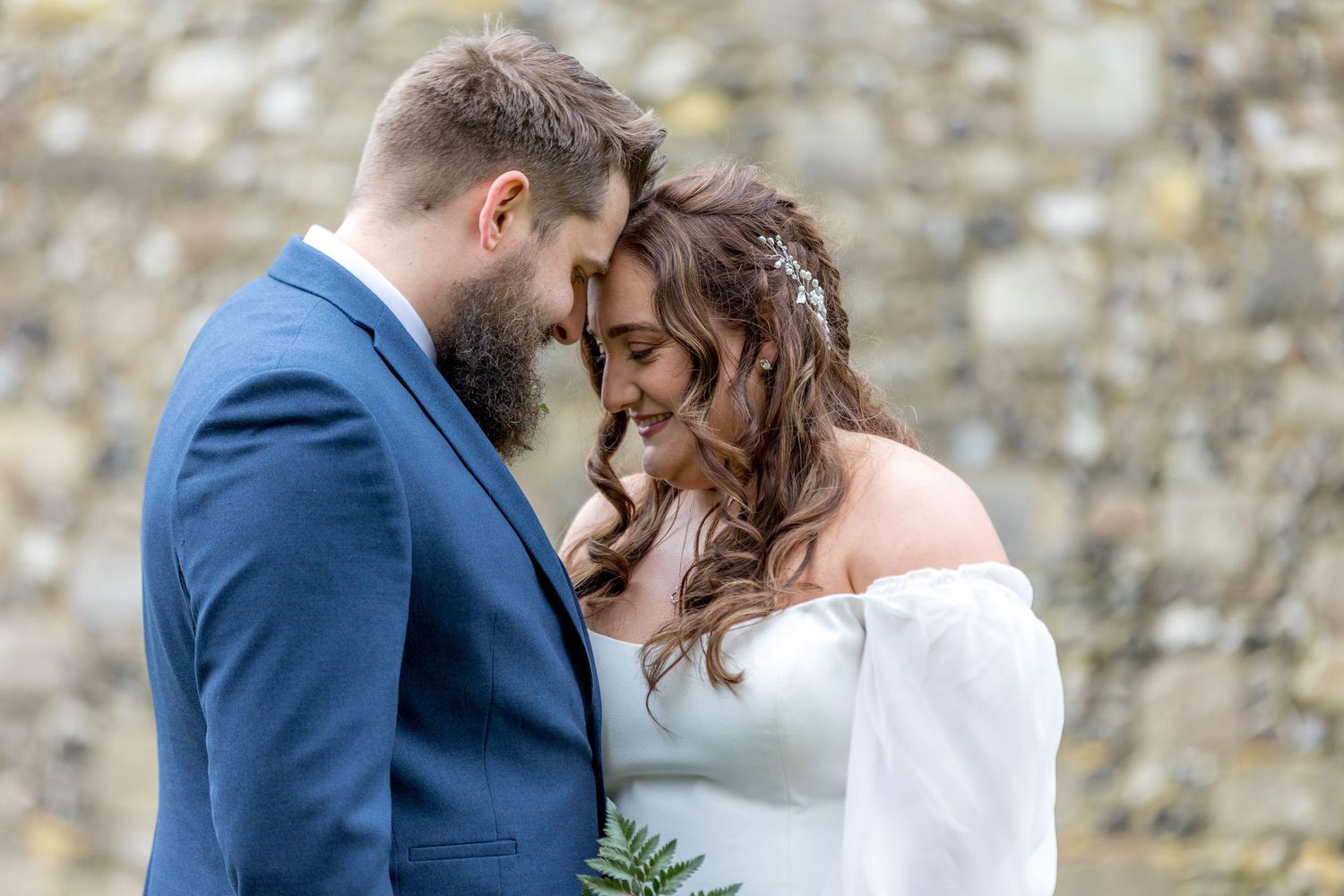 Romantic portraits against a rustic stone wall backdrop during a wedding celebration.