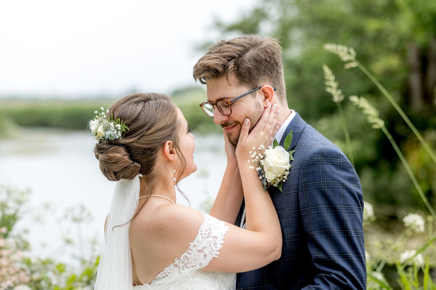 Romantic wedding couple shares an intimate moment in a lush garden setting with white flowers.