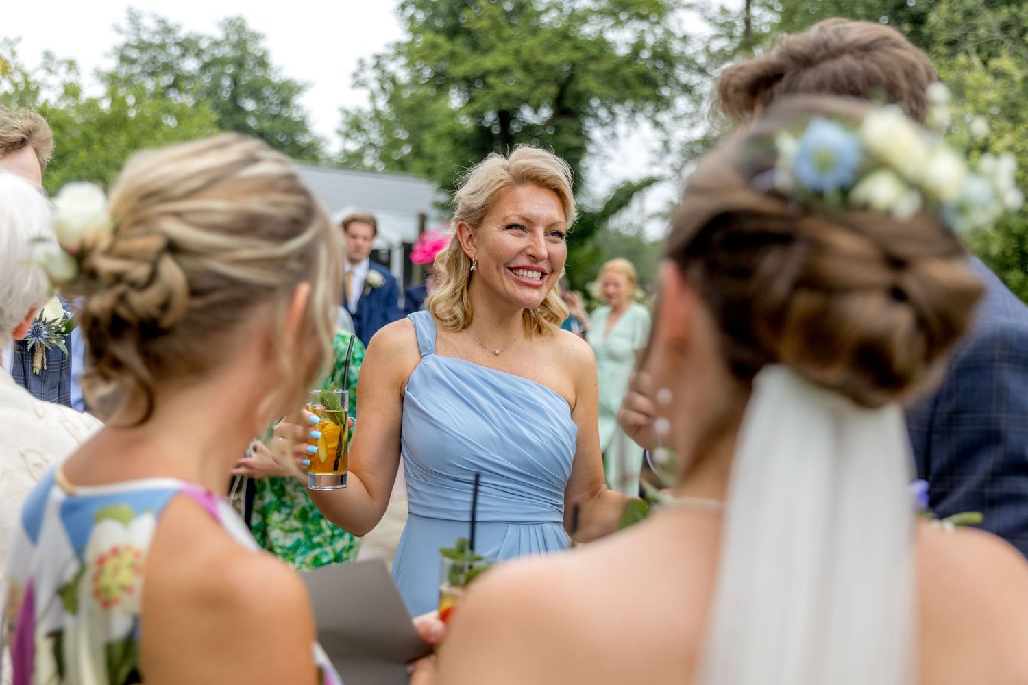 Joyful wedding guests celebrate outdoors with natural garden backdrop.