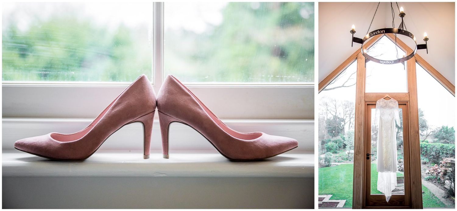 Pink bridal heels and wedding dress hanging in window light.