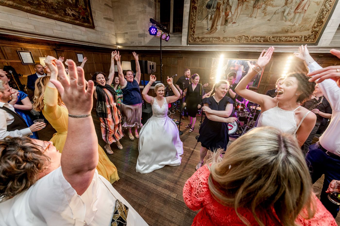 Wedding reception dance party with guests celebrating in an ornate historic venue.