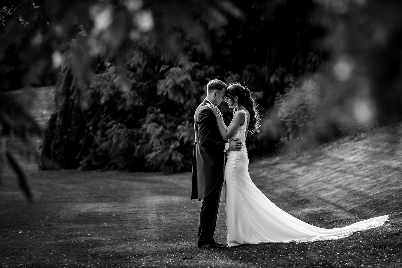 Dramatic black and white wedding photography in a natural outdoor setting.