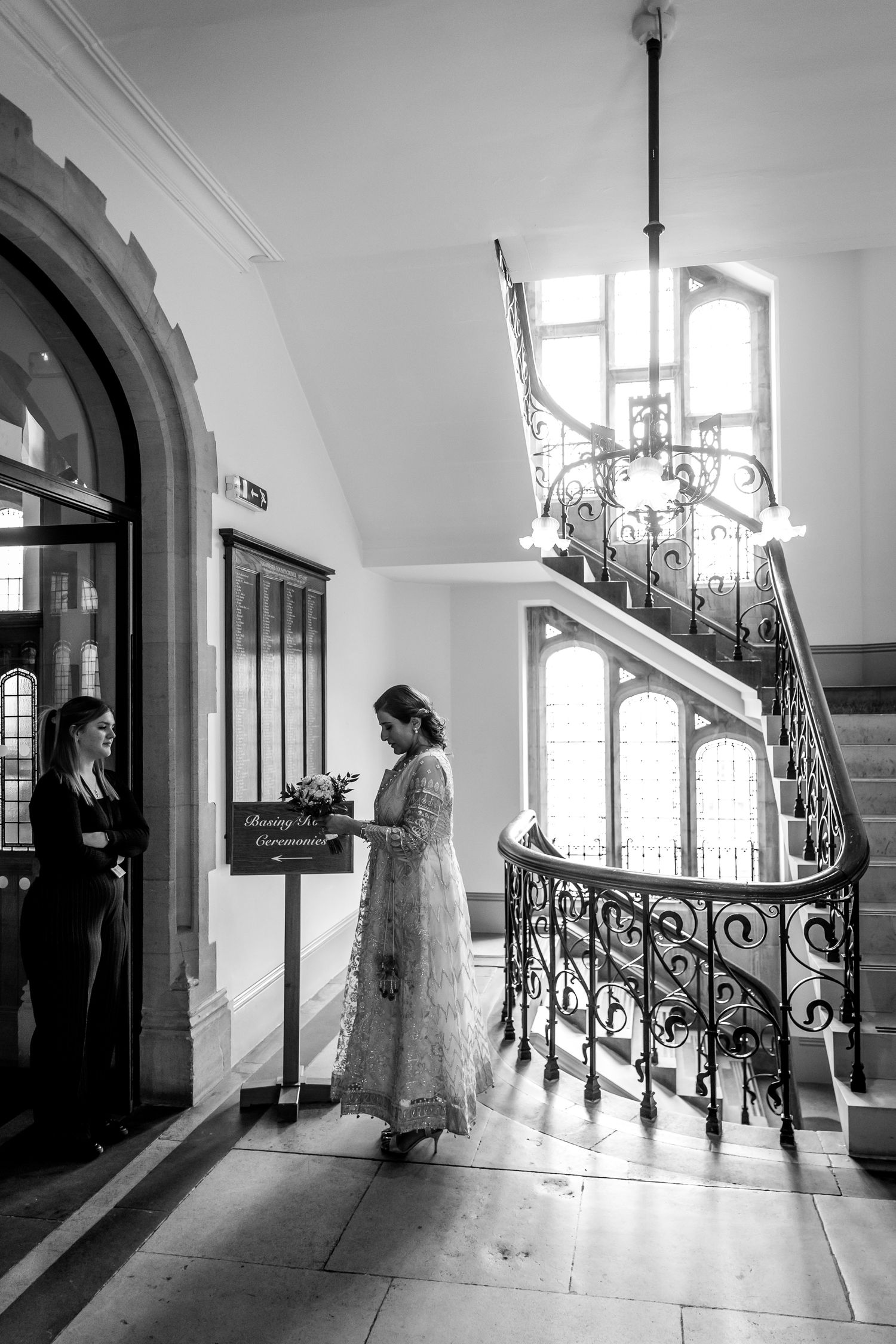 A black and white photo of an elegant staircase with ornate ironwork in a historic building.